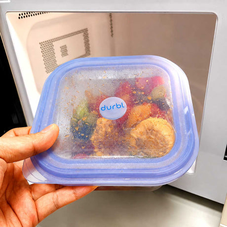 Durbl silicone lunch container with reheated meal in front of a microwave